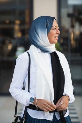 Hijabi Model wearing EMMA scarf Ebony North, in the Ombre colors of black and offwhite looking afar