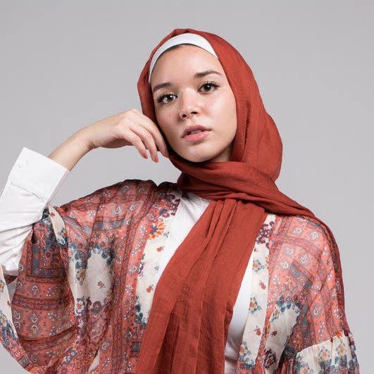 close up of hijabi model in EMMA Scarf Basic Maple staring at camera with her hand on her cheek