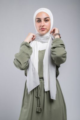 half body shot of hijabi Model in EMMA Scarf Silver Sugar , eyes smiling at camera with her hand on her neck