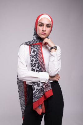 Hijabi looking at camera in EMMA Scarf Aztec Rouge with her hand under her chin