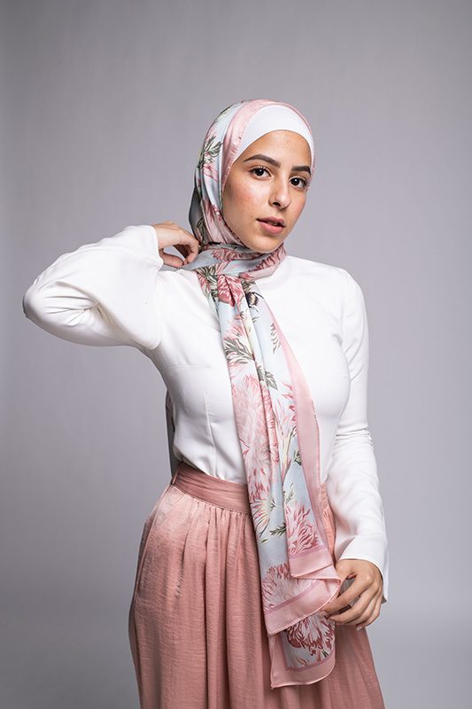 Hijabi Model in EMMA scarf Honey Blooms satin, a print of bees and delicate pink flowers with a pink border.