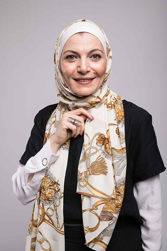 A close up f a hijabi woman in EMMA scarf Chains D'ior smiling