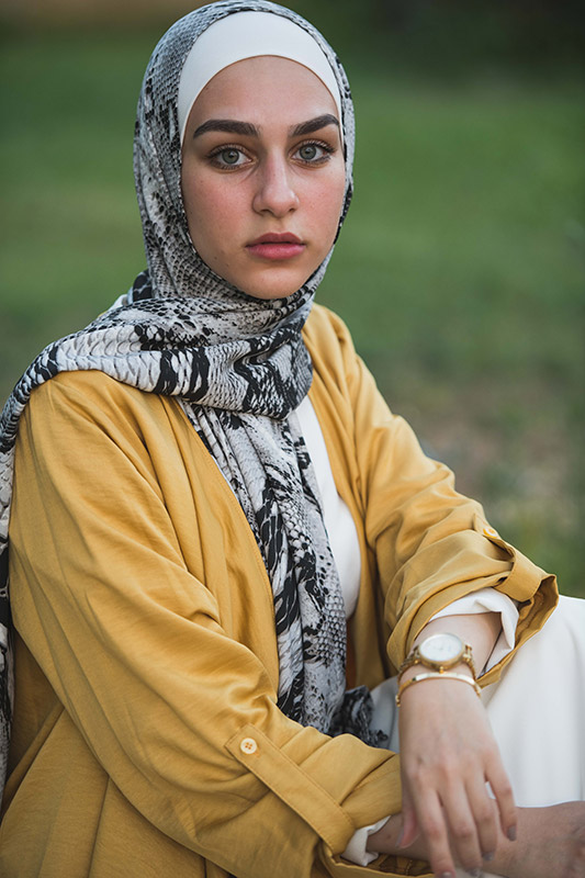 Close up of a hijabi model in EMMA Scarf Black Pythpn staring at camera in a yellow kimono