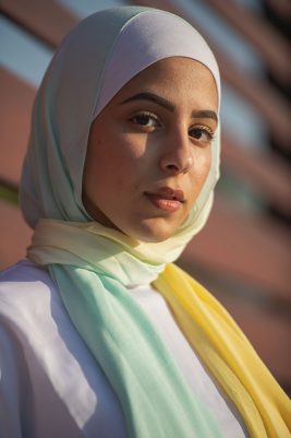 A close up of hijabi model in EMMA Scarf Kiwi Zest an ombre of yellow and light blue-mint.smiling while staring at camera