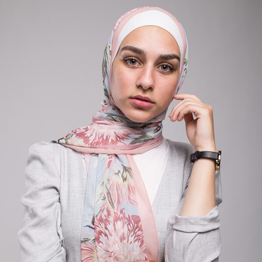 close up Hijabi Model in EMMA scarf Honey Blooms Chiffon, a print of bees and delicate pink flowers with a pink border.