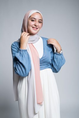 Hijabi Model in EMM AScarf Peach n Vanilla in a low cut shirt and a white skirt smiling at camera