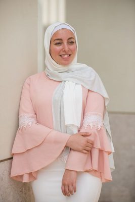 hijabi model in EMMA Scarf Silver sugar looking to the side holding her elbow in a pink ruffled top