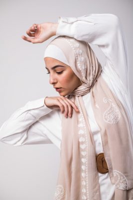 a nude scarf with paisley embroidered in the middle and white hearts embroidered on the border